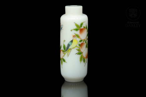 Enamelled glass monkfish bottle, Qing dynasty: Glass snuff bottle, white color, and enamelled on the outside, with a classic design of a bird on a branch of peaches, flowers and butterflies. On the base is a Qianlong four-character seal " ???? "