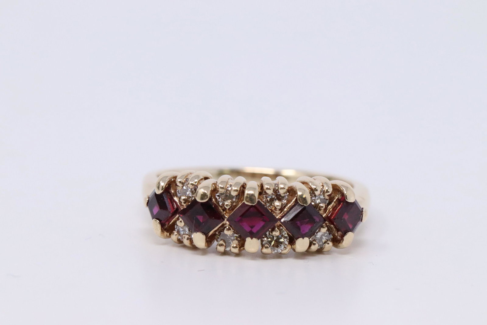 14Kt Diamond Ring w/ Garnets: A ladies 14kt Yellow Gold Diamond ring. Ring has a total of 8 round brilliant diamonds and 5 Square Cut Garnet stones set on the center. Diamonds weight approx 0.19ctw. Ring size: 6.00. Total weight: 