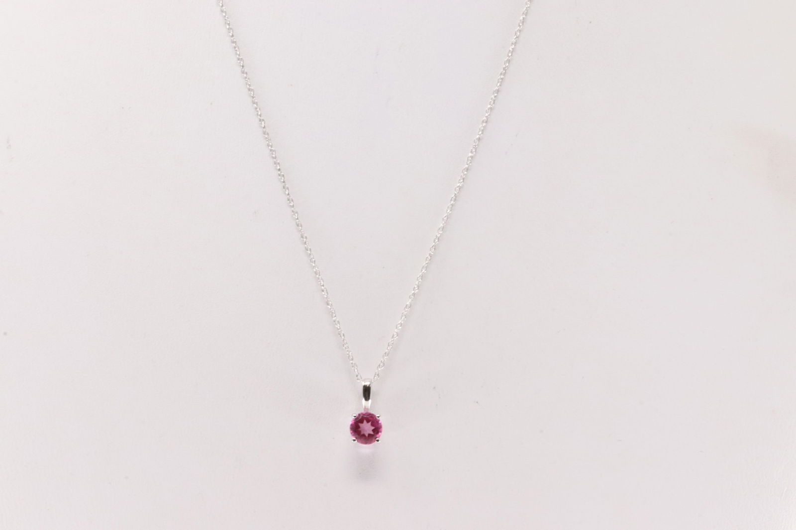 Pink Topaz Necklace 10Kt.: Ladies 10Kt White Gold Pink Topaz Necklace. This Necklace has Charm with a round Pink Topaz. Topaz Measure: 5mm. Necklace length: 18.00"