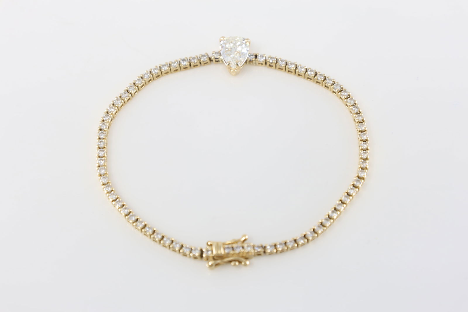 EGL Pear Diamond Tennis Bracelet 14Kt.: EGL 14Kt Yellow Gold Pear Diamond Tennis Bracelet. This tennis design has one Pear-shape Brilliant Diamond in the center with a total of 70 round cut diamonds to the sides. Diamond-Pear weight: