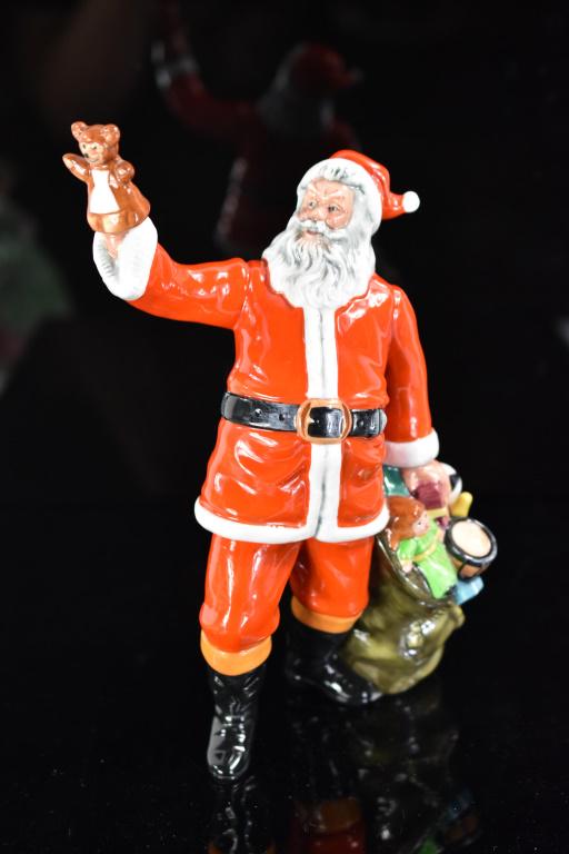 Royal Doulton Santa Claus Porcelain Figure: Santa Claus Holding Teddy Bear and Sack of Toys. Designed by Artist William K. Harper and Issued 1982-93. Measures approx. 9.75" Tall. Marked "HN 2725" and Royal Doulton Mark printed with "Royal Doult