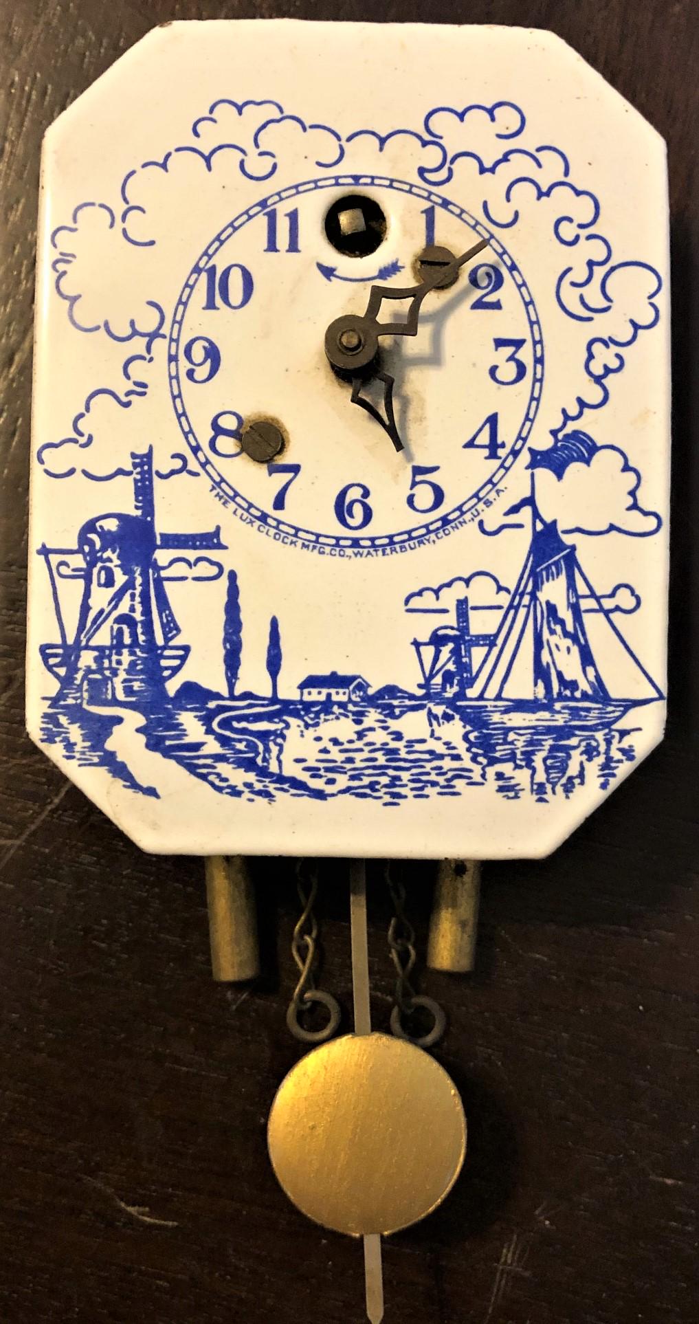 PORCELAIN / ENAMEL BLUE / WHITE DUTCH MILL PENDULETTE: WALL CLOCK - 'DUTCH SCENE' W/ DUTCH MILL AND BOAT - BLUE AND WHITE - LUX CLOCK MFG. CO. INC. WATERBURY CONN. U.S.A. - 2 5/8" X 8 3/8"