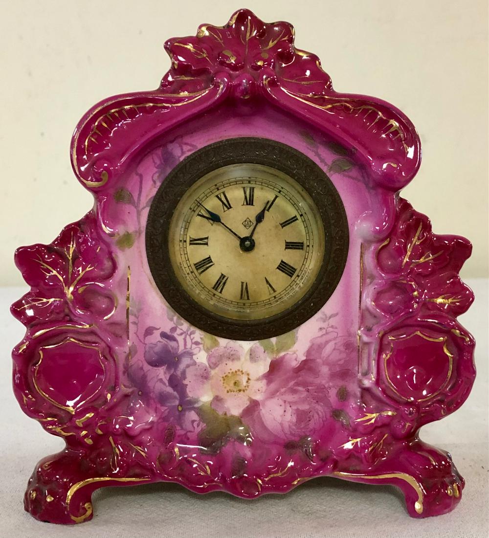 MINIATURE GERMAN ROYAL BONN PORCELAIN SHELF CLOCK: GERMAN "GAZELLE" PATTERN ROYAL BONN CLOCK MARKED ON BACK WITH ROYAL BONN LOGO - ANSONIA BRASS WORKS - FUSCHIA WITH GILT HIGHLIGHTS AND FLORAL DECORATION - WORKING WHEN TESTED - NO CHIPS, CRACKS OR REP