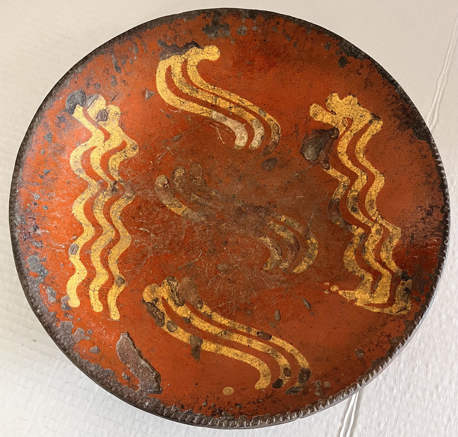 LG. 12 1/4" 19TH C. SLIP DECORATED REDWARE PLATE: LG. 12 1/4" 19TH C. SLIP DECORATED REDWARE PLATE WITH YELLOW SLIP DECORATION - COGGLED EDGE - NO CRACKS BUT CHIPS / GLAZE LOSS - LOSSES TO THE BOTTOM BUT SOLID - 12 1/4" DIAMETER