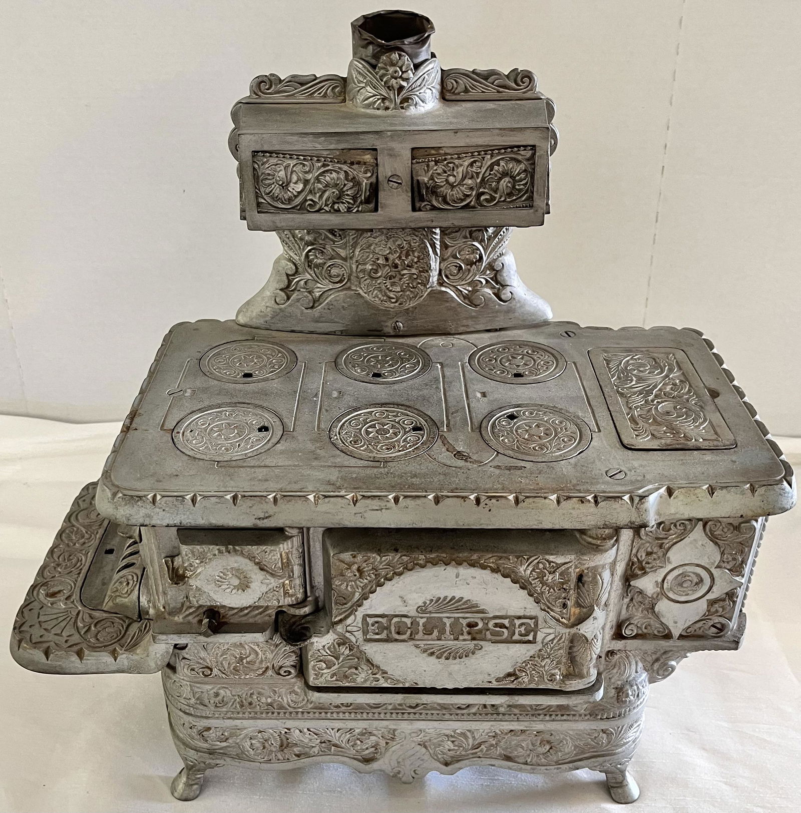 ELABORATE MINIATURE VICTORIAN "ECLIPSE" CAST IRON STOVE: ELABORATE MINIATURE VICTORIAN "ECLIPSE" CAST IRON STOVE BY J. & E. STEVENS COMPANY - HEAVILY EMBOSSED DECORATION ALL THE WAY AROUND - COMPLETE AND IN EXCELLENT CONDITION - 16" HIGH X 16" WIDE X 9 1/4"