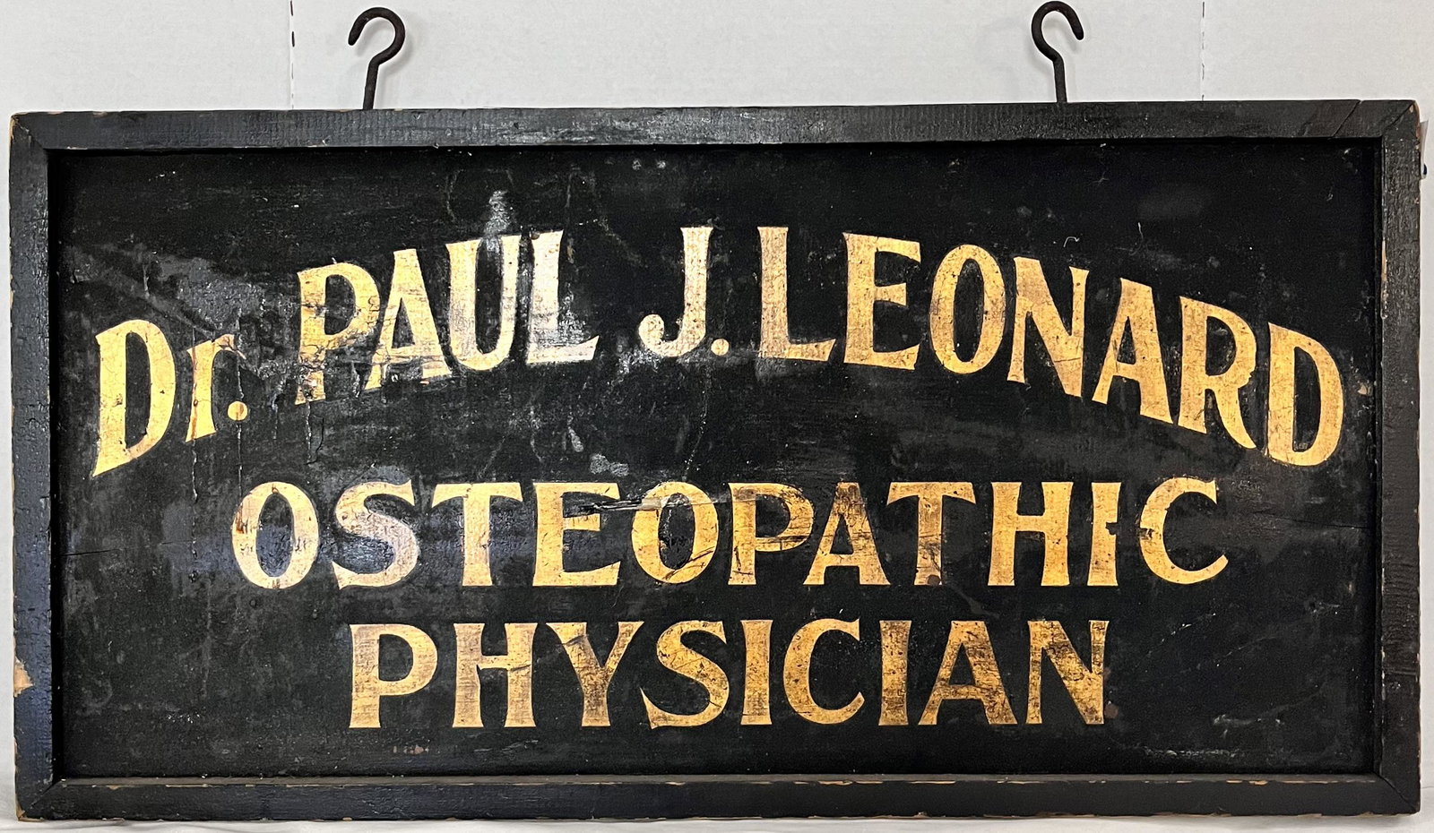 2 SIDED WOODEN PHYSICIAN SIGN - BLACK WITH GOLD GILT LETTERING: 2 SIDED WOODEN PHYSICIAN SIGN - BLACK WITH GOLD GILT LETTERING - READS "DR. PAUL J. LEONARD OSTEOPATHIC PHYSICIAN" - 33" WIDE X 16 5/8" HIGH X 1 3/4" THICK - GILT LETTERS MEASURE 1 3/4" HIGH