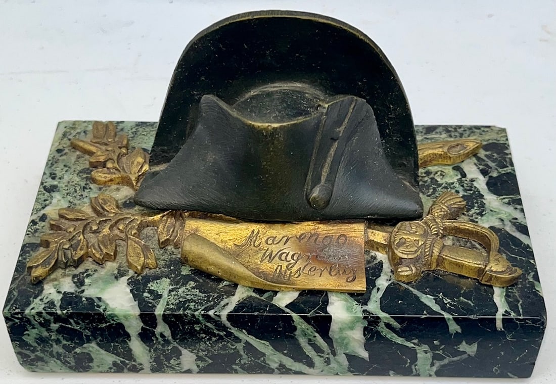 NAPOLEON'S HAT & TROPHY OF ARMS FRENCH DORE & MARBLE OFFICERS INKWELL: NAPOLEON'S HAT AND TROPHY OF ARMS FRENCH DORE AND MARBLE OFFICER'S INKWELL- SCRIPT READS "MARENGO WAGRAM AUSTERLITZ" - GLASS INSERT INTACT (HAS CHIP ON RIM) - MEASURES 5 3/4" X 3 3/4"