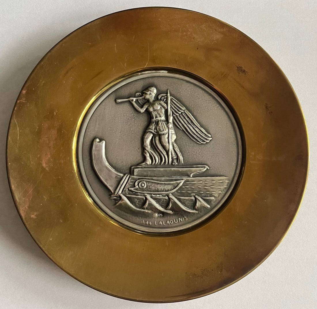 Ilias Lalaounis Greek Revival Sterling Silver Medallion Plaque, Trireme & Winged Warrior Design: An impressive collectible medallion by acclaimed Greek designer Ilias Lalaounis, featuring a high-relief sterling silver center inset into a golden bronze or brass round plaque. The central scene is d