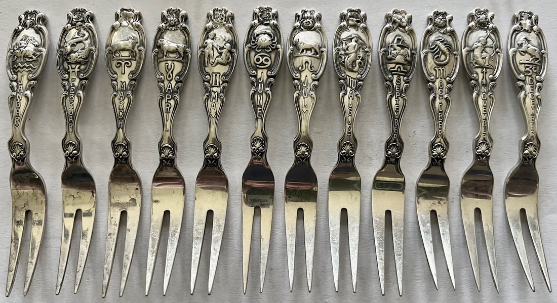 Set of 12 Sterling Silver Zodiac cocktail forks with embossed month, Zodiac symbol & flower, 156.84g: Set of 12 Sterling Silver Zodiac cocktail forks with embossed month, Zodiac symbol & floral decoration, All embossed on reverse with "Sterling", "Pat. Oct. 9.1894" and maker's marks, total weight 156.