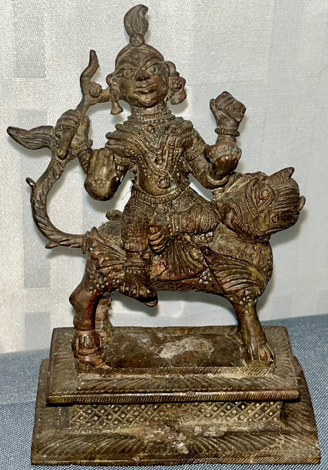 Bronze Indian Deity Durga on Lion, Tribal Bastar Folk Art, India: Bronze Indian Deity Durga on Lion, Tribal Bastar Folk Art, India, A cast bronze figure of the Hindu Goddess Durga, depicted in a traditional pose riding a lion, symbolizing the victory of good over ev