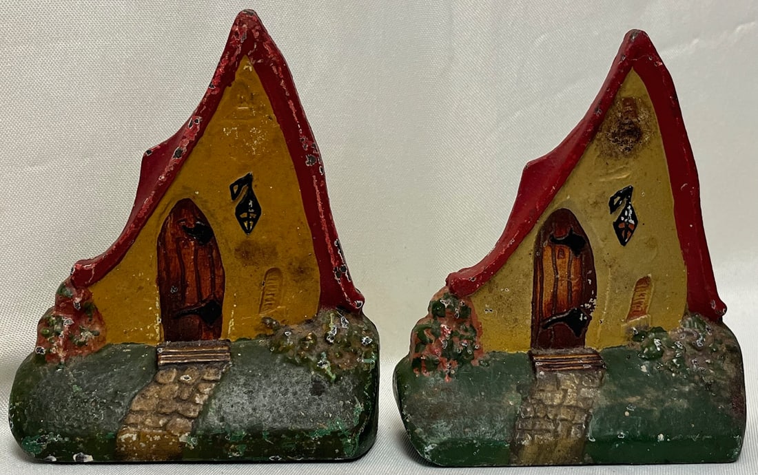 Pair Antique Cast Iron Cottage Bookends | Hand-Painted Folk Art House | c. 1920s–30s: matched pair of antique cast iron bookends featuring a whimsical storybook cottage / fairy house design. Each bookend is solid cast iron with hand-painted details, including a peaked red roof, yellow