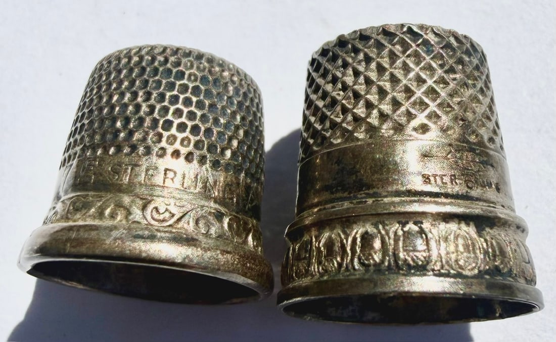 Lot of 2 Antique Sterling Silver Sewing Thimbles, 4.13 Grams: Lot of two antique sterling silver sewing thimbles, each with a different textured pattern. One features a fine honeycomb-style dimpled surface with decorative scrollwork around the lower border; the