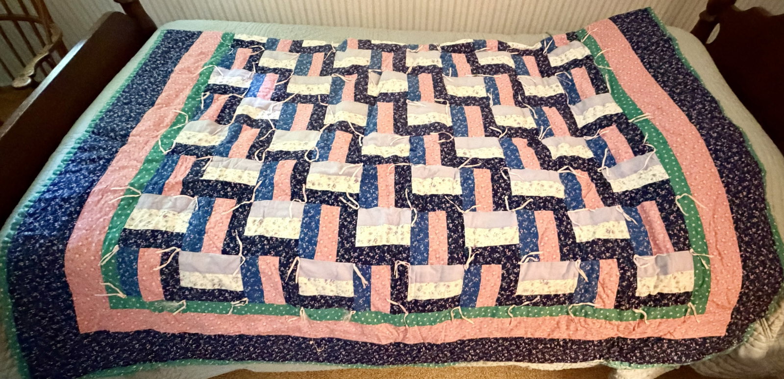 Vintage Hand-Tied Patchwork Quilt, Mid-20th Century: Vintage American patchwork quilt constructed in a colorful geometric woven or interlocking pattern using small floral-print cotton fabrics in navy blue, salmon pink, green, cream, and lavender,