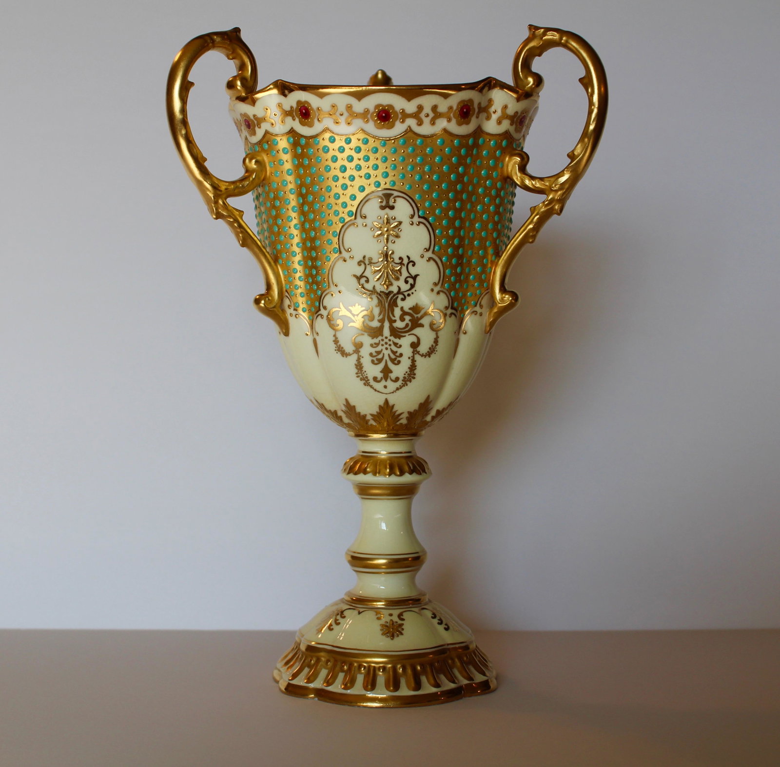 Coalport Jeweled Loving Cup: Coalport jeweled loving cup or chalice turquoise jewels set on gold with a cream/yellow background color. Height 8.5 inches.