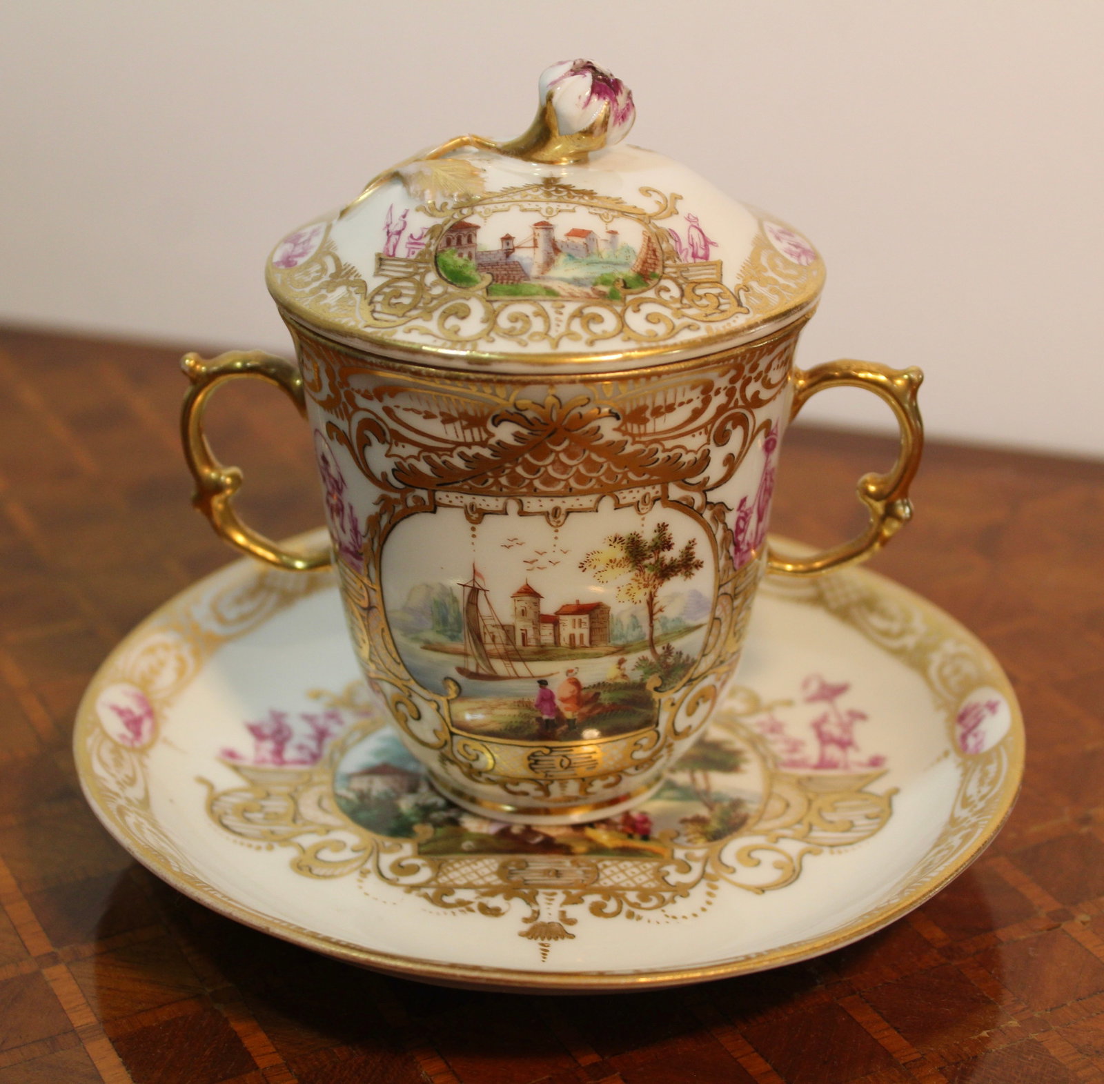FINE MEISSEN ANTIQUE CHINOISERIE CABINET CUP AND SAUCER: Antique Meissen cabinet cup and saucer with lid decorated in a chinoiserie style with 18th century landscape scenes and elaborate gold gilt workmanship.