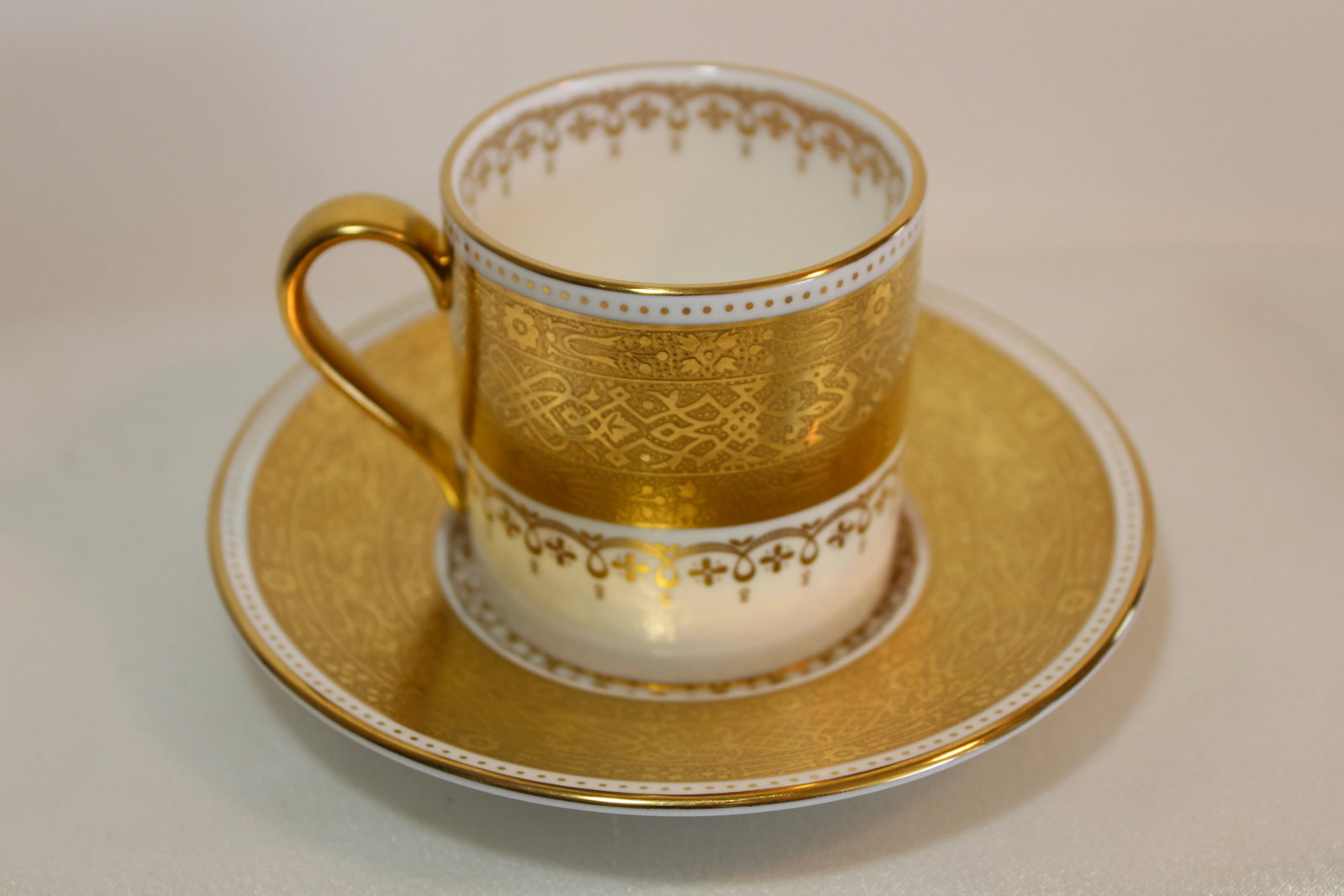 MINTON DEMITASSE CUP AND SAUCER: Antique Minton demitasse cup and saucer with elaborate gold decoration and red background color.