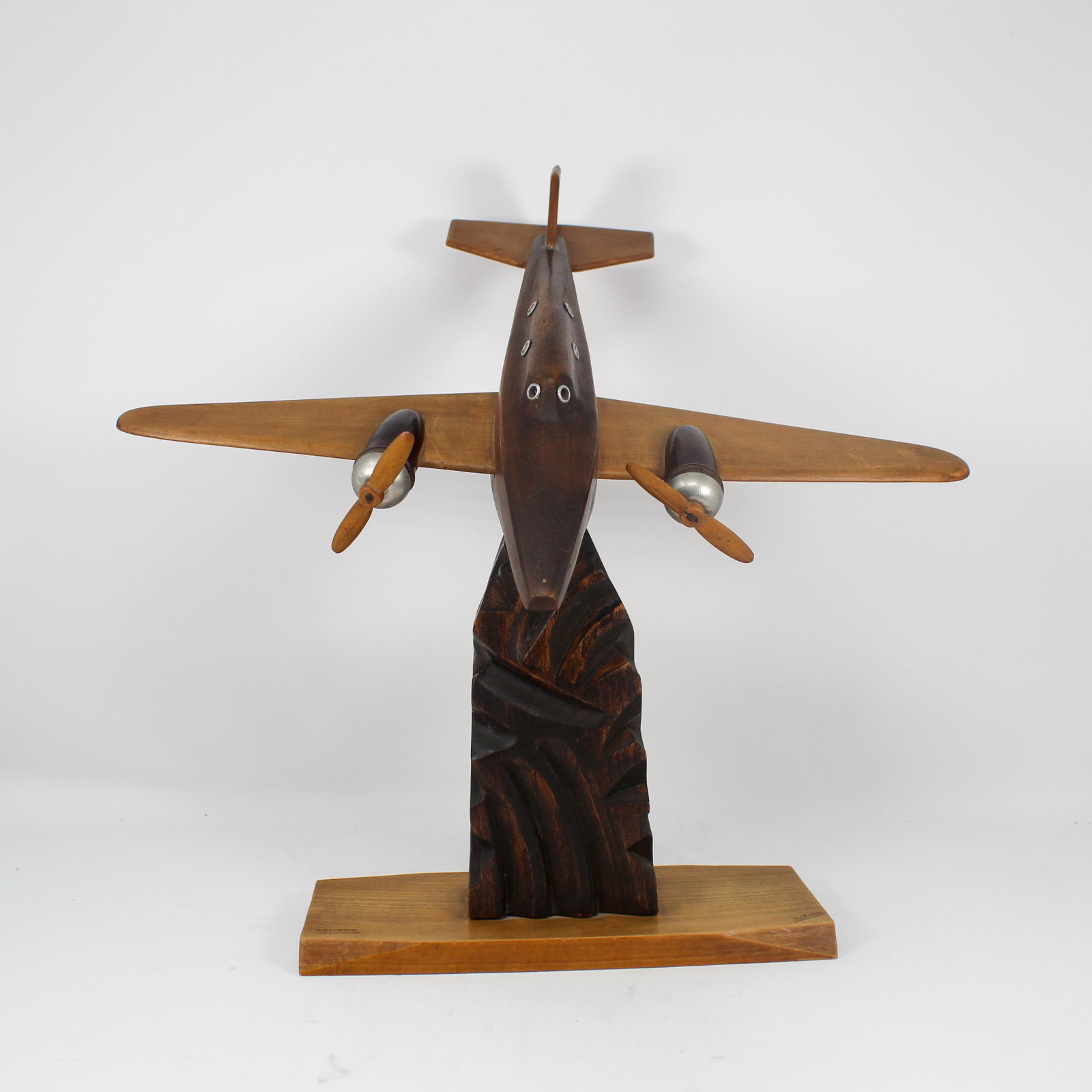 CLASSIC ART DECO WOODEN AIRPLANE DESK ORNAMENT: Designed by the Anthoine Art Bois studio Made of solid light varnished wood with chromed metal accents on a carved wood â€œwave” plinth and two wooden propellers that spin The plane is attac