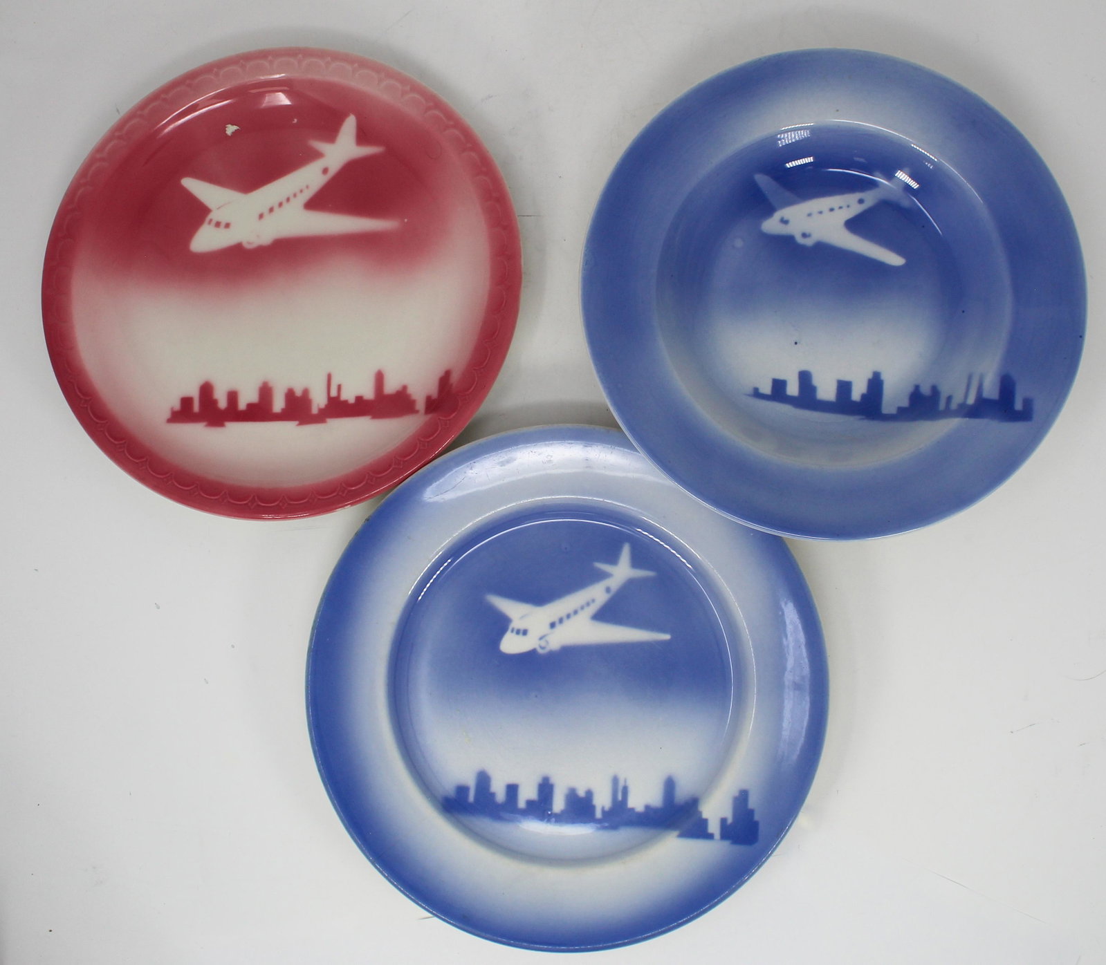 VINTAGE SYRACUSE CHINA WITH AIRPLANE MOTIF: A selection of very hard-to-find dinnerware made by the Syracuse China Corp., featuring an airplane flying over a city skyline. All are marked â€œO.P.CO. [for Onondaga Pottery Company, its origina
