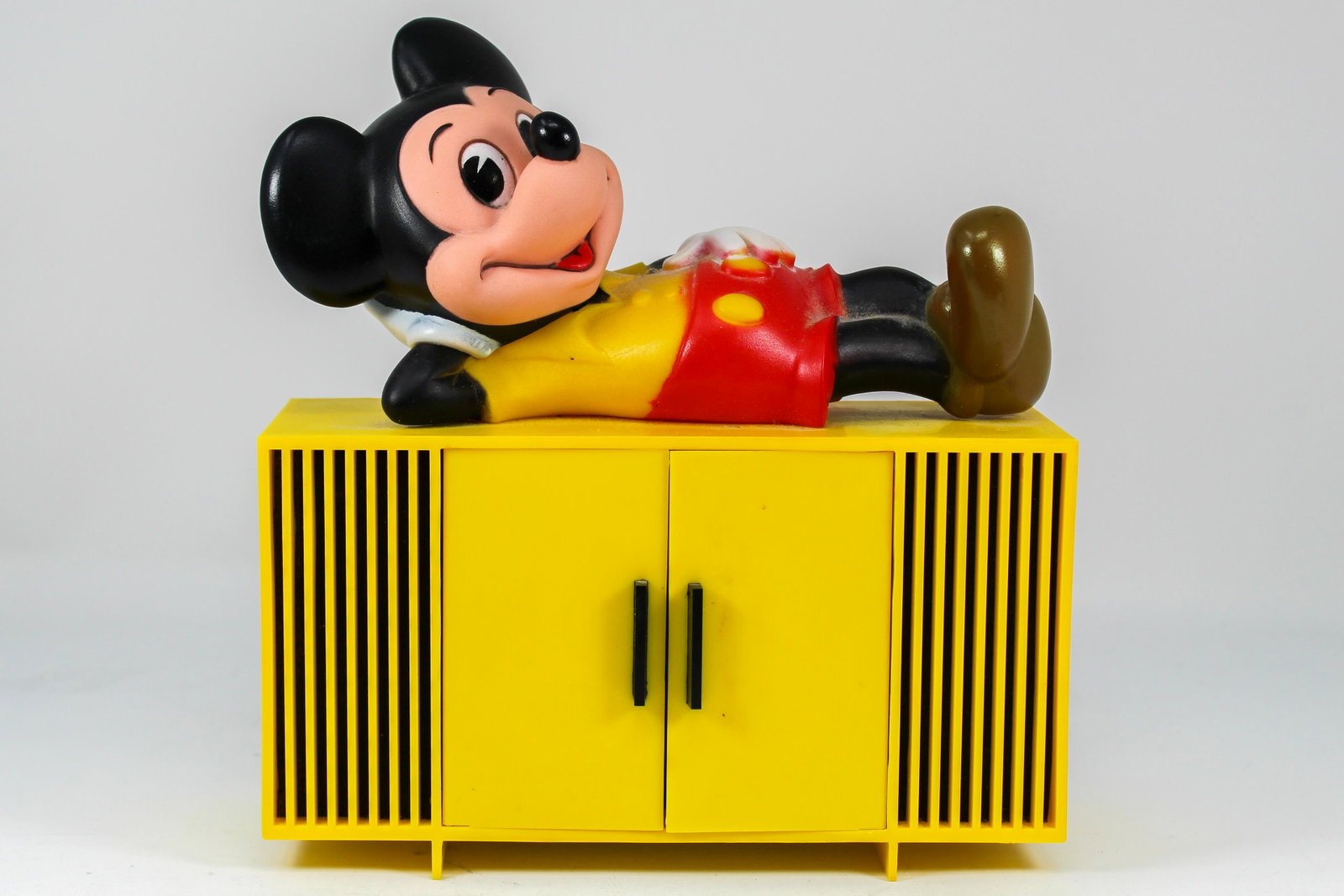 MICKEY MOUSE CABINET AM RADIO: Circa 1970's, model 407 manufactured by Concept 2000. Mickey lounges on top of the yellow cabinet. The two doors open to reveal the on/off and tuning knobs, exc. working condition with no cracks or ma