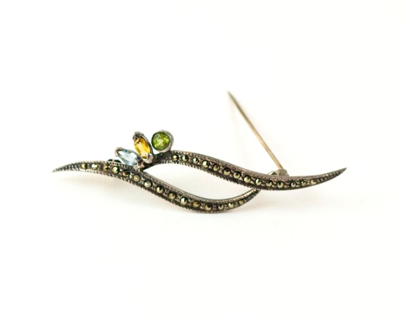 VINTAGE STERLING SILVER PIN MARCASITE PERIDOT TOPAZ: Vintage STERLING SILVER Pin features two swirls set with Marcasites as well as a Peridot, Blue Topaz and Golden Topaz. The pin is 2 3/4 inch across.