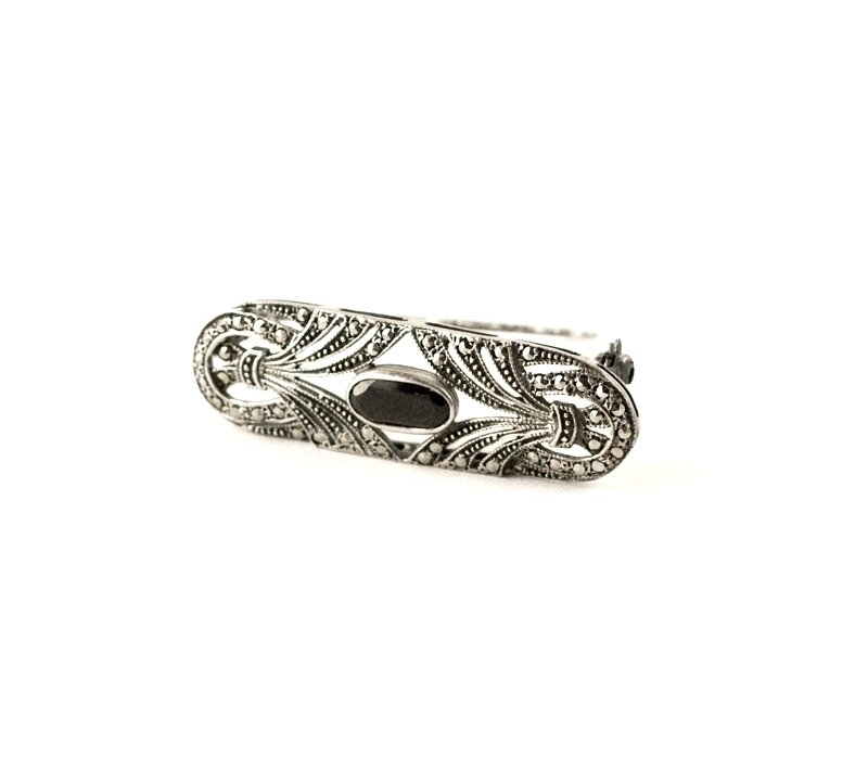 ART DECO PIN BLACK ONYX AND MARCASITE STERLING SILVER: This Antique Art Deco Sterling Silver Bar Pin Brooch features an elongated Oval BLACK ONYX surrounded by openwork set with Marcasites. The pin measures 1 3/4 inches x 5/8 inch.