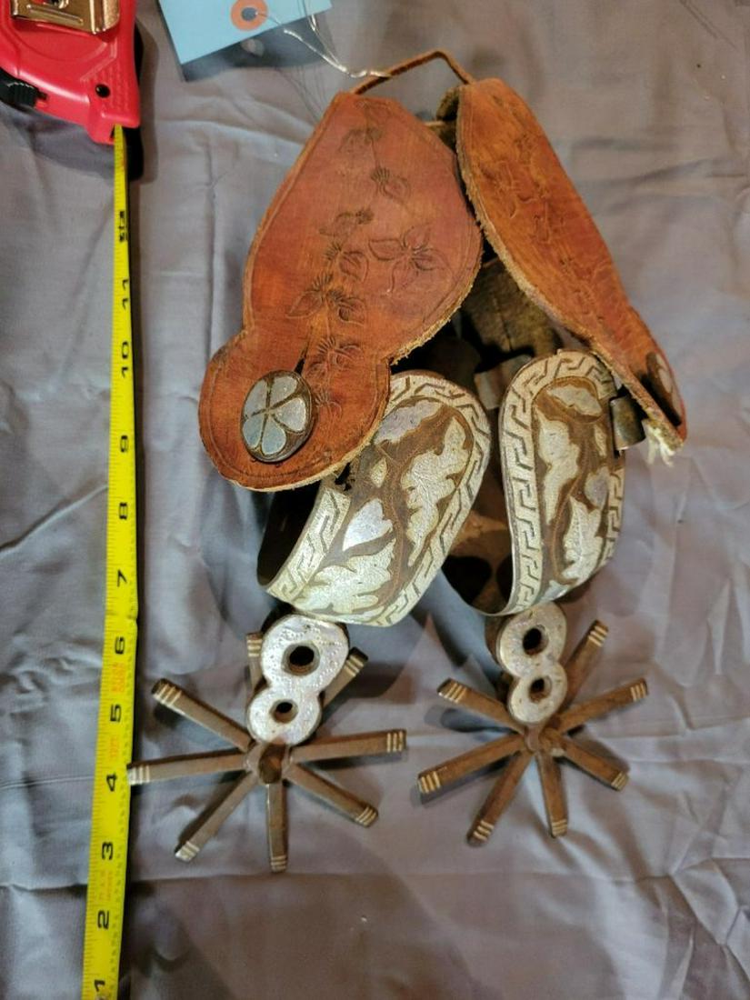 Pair of ornately engraved spurs with leather straps: .