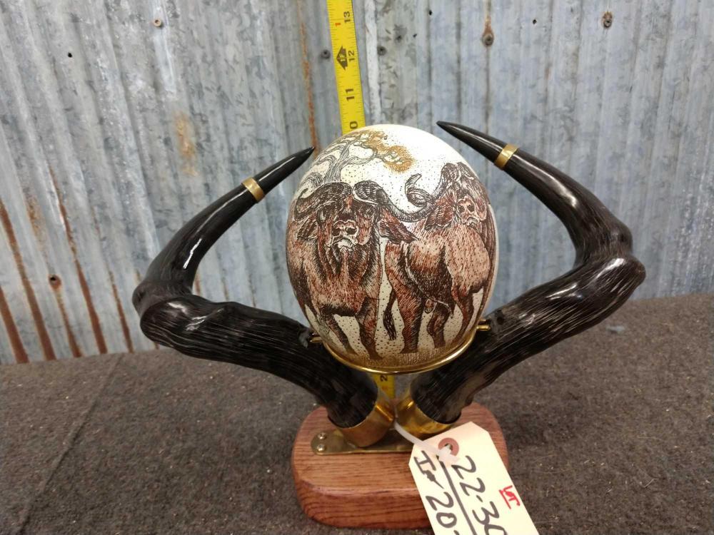 Scrimshawed Ostrich Egg Framed With polished Wildebeest: Scrimshawed Ostrich Egg Framed With polished Wildebeest Horns 22.30 Highly detailed egg featuring Cape Buffalo framed with wildebeest horn mounted in African hardwood base hand crafted In South Africa