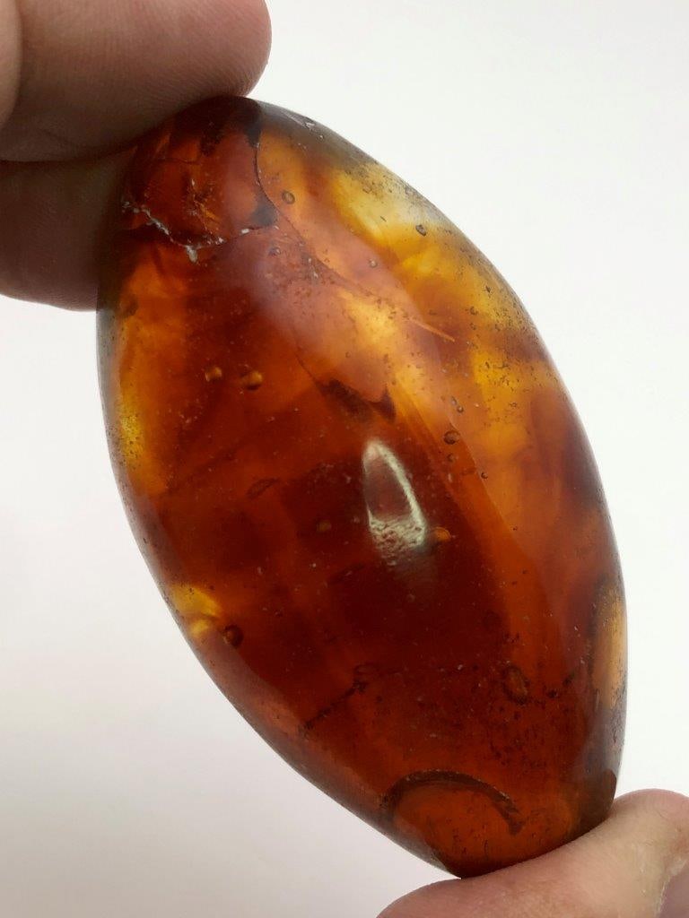 Carved Natural Glass Egg with Golden Inclusions ? 129 g Decorative Mineral Specimen: This beautiful hand-carved natural glass egg weighs 129 grams and features striking golden inclusions suspended inside the translucent glass. The smooth egg shape highlights the natural internal patte