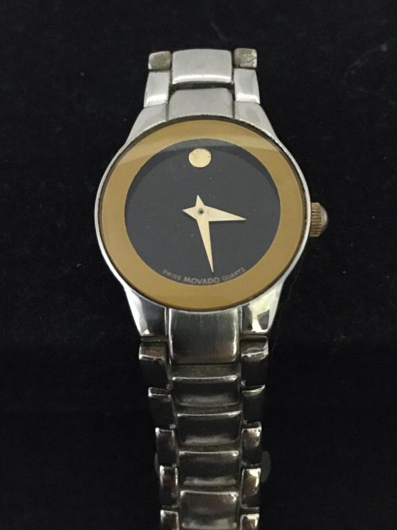 Ladies Movado Wrist Watch: Museum Watch, black face, no markings on face, just 2 hands and a dot for the 12, stainless steel band, 7" long needs battery, minor scratches on band
