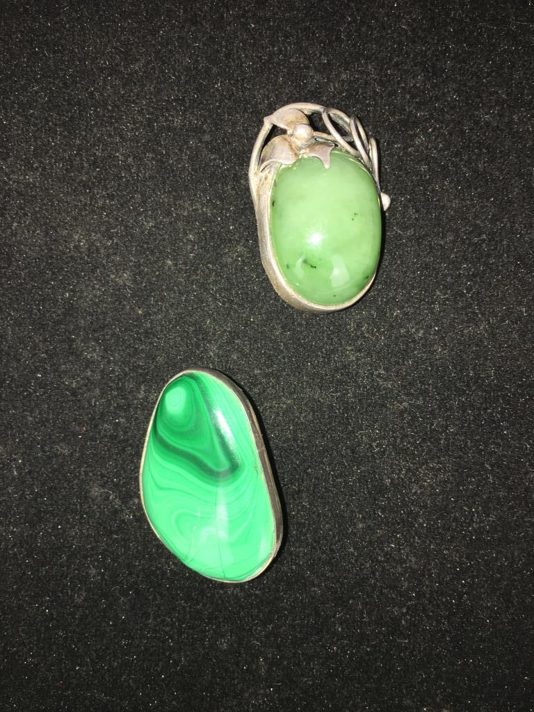 2 Pins, 925 sterling: one Malachite Pin/Pendant. marked 925 (5 is worn off), locking fastener, 1 1/2" l x 1" and one oval cabochon green stone (possibly jade) pin/pendant with floral décor at top, 925 and the 9 is worn, 1