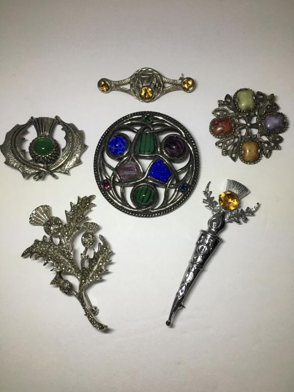 6 Scottish Thistle Pins: no pins are sterling, 1 Soolor Brooch with multi colored stones, 2 1/4", 1 Weiner Brooch with 4 different colored stones 1 1/2" d and 1 Mizpah Thistle Pin with yellow stone, 3", 1 marcasite thistle pi