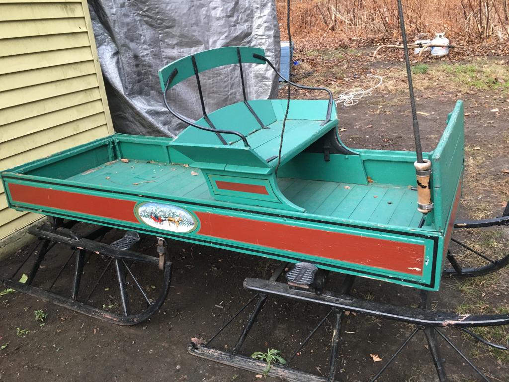 Horse-Drawn Buckboard Sleigh & Shaft: with 12 ' whip, Red and Green, one-seater (back seat is missing), back end of wagon opens, oval medallion of sleigh ride on each side, 2 runners, foot rest, 4 metal steps, shaft is 8' l, 54" long sled
