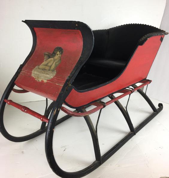 Child Size Sleigh: decoupage angel on front, curved back iron runners, leather seat and back with brass studs, 34" l x 17 1/2" w x 19" h some paint loss, damaged front, broken front curved piece, back handle is missing 