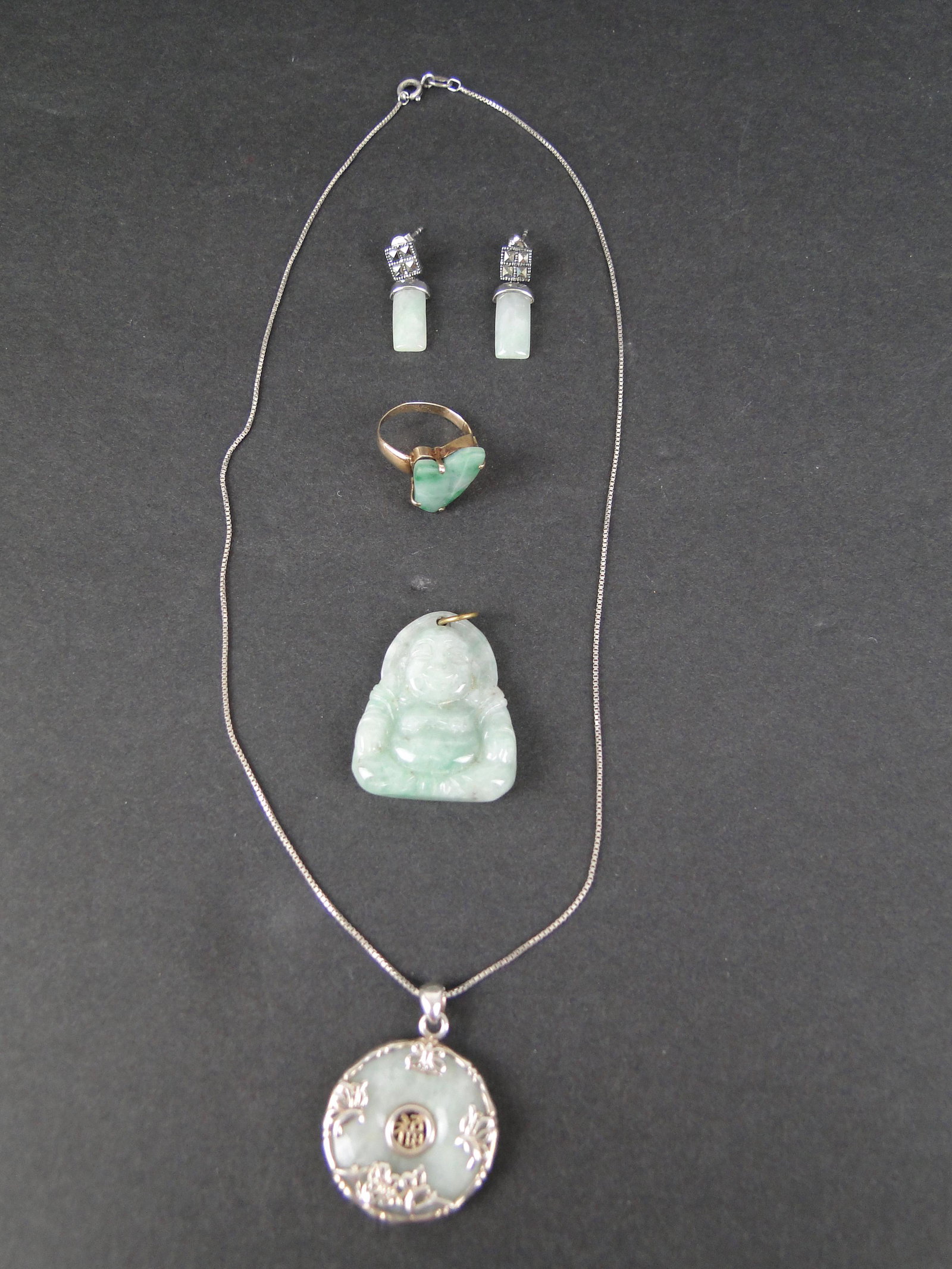 Lot of 4 Jade Items: 14K yellow gold (tested) ring with etched Jade stone, size 5, carved Buddha pendant 1 1/2" h, pair of .925 China 1" l Jade and marcasite pierced earrings, Jade circular .925 pendant with flowers on 18