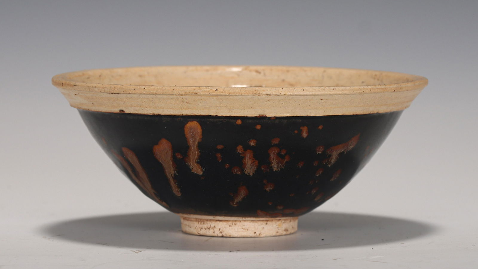 A CHINESE JIZHOU TYPE GLAZED PORCELAIN TEA CUP: H. 6.5 cm. W. 15.2 cm.