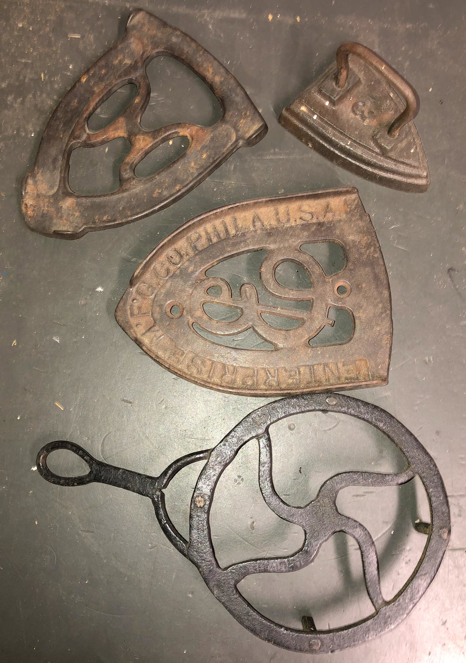 Trivits & 1 child's flat iron: 1 Enterpise trivet, 1 hand forged trivet, and 1 un-named.