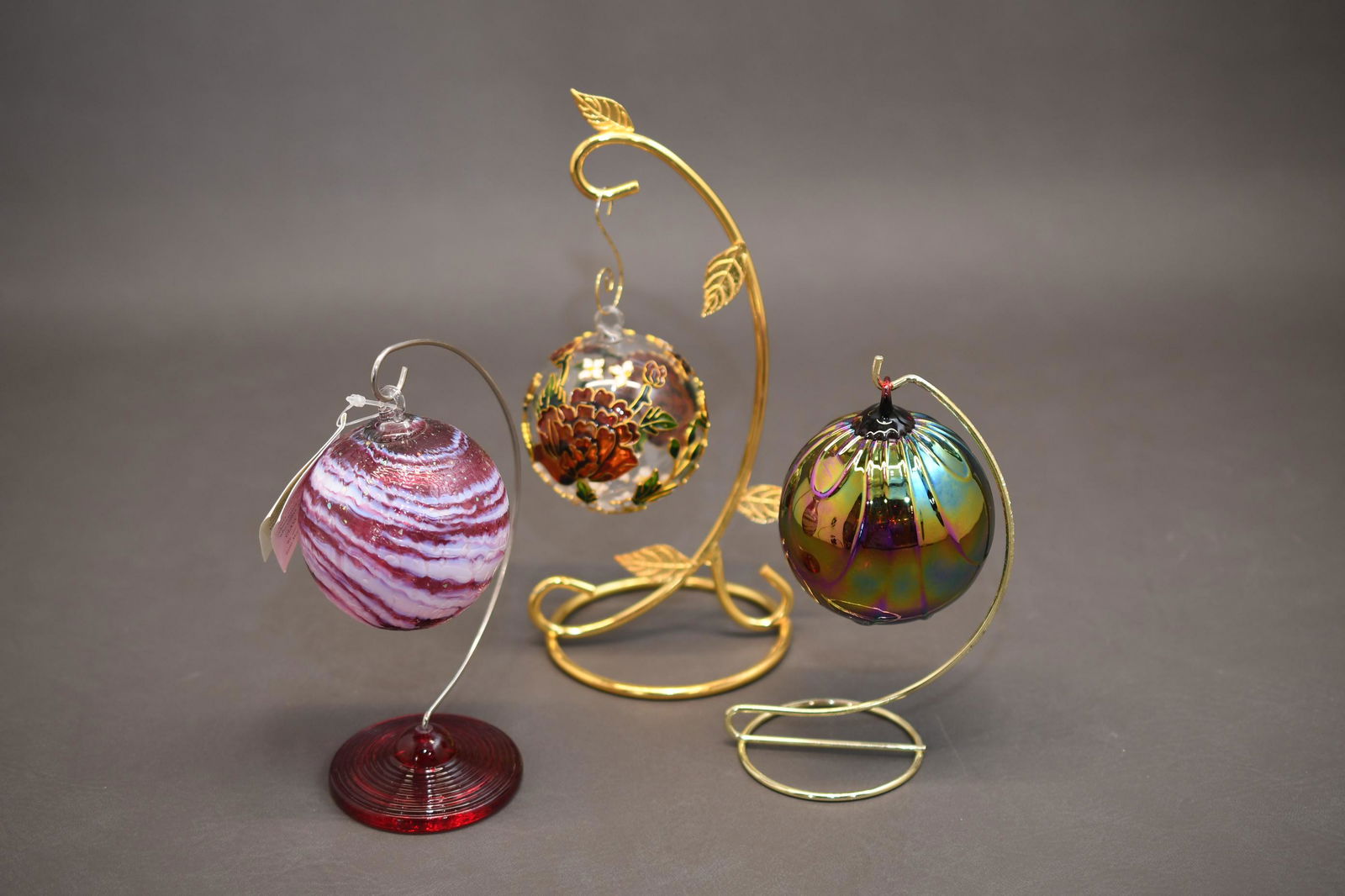 Three Art Glass Ornaments: 3" diameter each, Glass Eye Studio hand blown "blast from the past" on stand, Applied flowers to glass ornament on stand, iridescent art glass on stand, approximate total weight 1lb