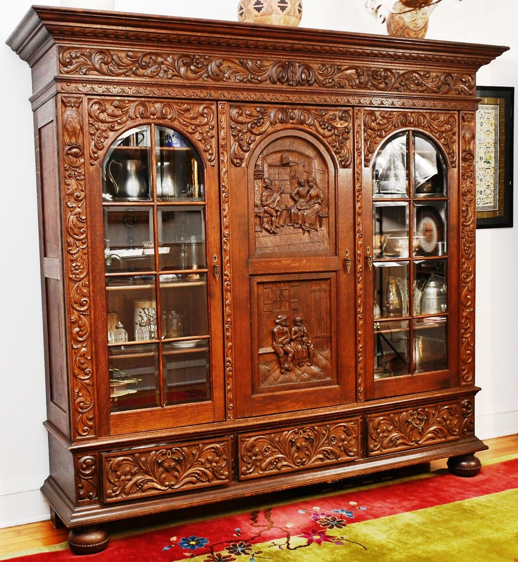 German Bookcase Antique heavily carved Oak: All Original .Crown-84 3/4"x21". Knockdown Full Cabinet Center Body- 76 3/4" W x 16 7/8" D. 3 doors,( two glass doors piano hinges, center door are pin hinges)- 25"W x 50 1/4"T x 14 1/4" D. Oak Shelve