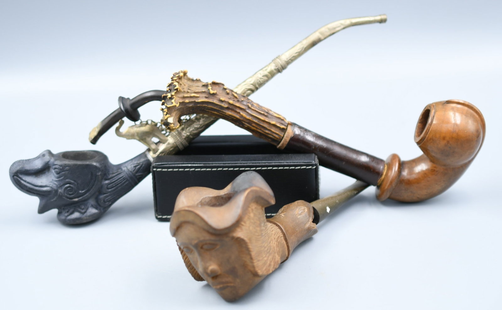 Tobacco Pipes: 3 pipes; 1 Carved Head wood pipe, 1- Vintage clay elephant head, embossed long stem, 1-Long stem, wood and bone and leather. (NOTE-Weight and dimensions are before packaging) Elephant pipe-bowl dia-1"