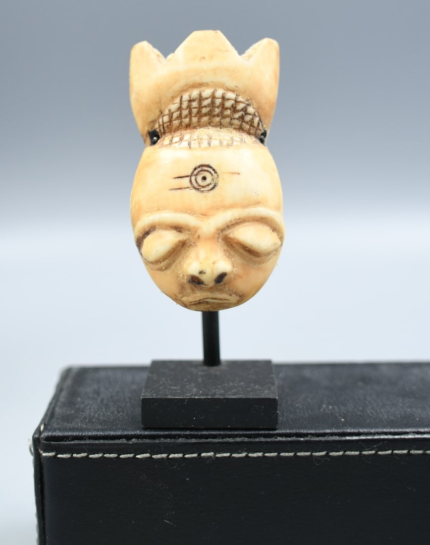 Antique African Bone Mask Pendant: African mask pendant carved from bone. (NOTE-Weight and dimensions are before packaging) pendant-2 1/4"L x 1 3/8"W. Weight-.75oz. Stand-1"x1"x2 1/4"T. Total Height-3". Combined weight- 2.10oz.