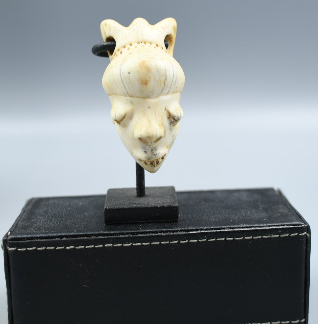 Antique African Bone Mask Pendant: African mask pendant carved from bone. (NOTE-Weight and dimensions are before packaging) pendant- 2 1/4"L. 1"D, 1"W. Weight-1.3oz. Stand-1"x 1"x 2 1/2"T. Combined height-2 3/4". Combined Weight-2.55oz