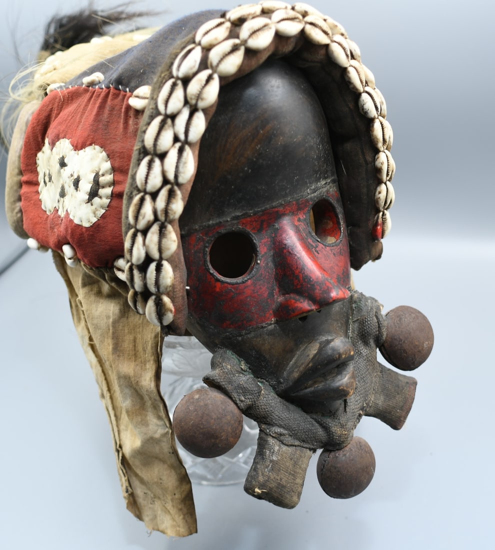 Dan tribe mask "Go Ge": Considerable age carved wood tribal mask accompanied by its Royal adornment of bells around the chin, real hair in the head dress. Sea shells and multiple fabrics make up the head dress. Dr Herz colle