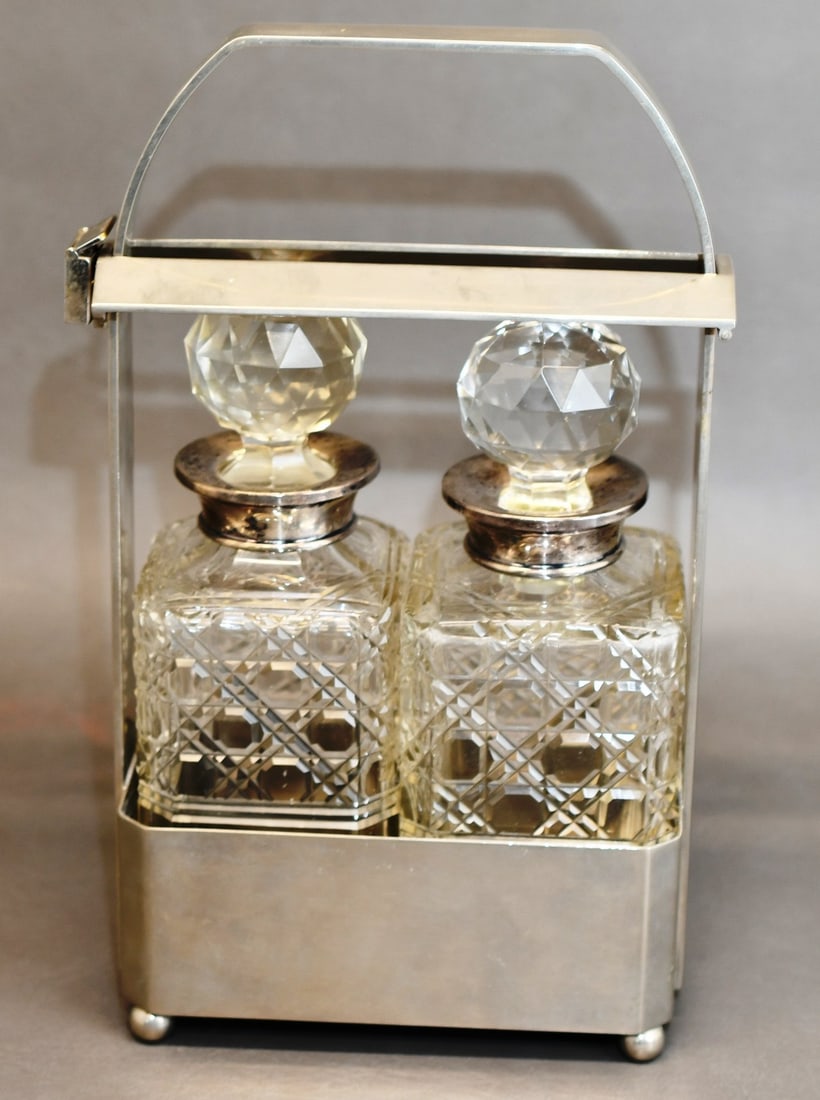 Locking Chrystal Decanter Set: 2 cut glass decanters with cut stoppers that rest in a silver colla, 1 stopper has a rub mark on top and sits on a slight angle but is a snug fit.one has a larger diameter hole about 1.5" vs about 1-1