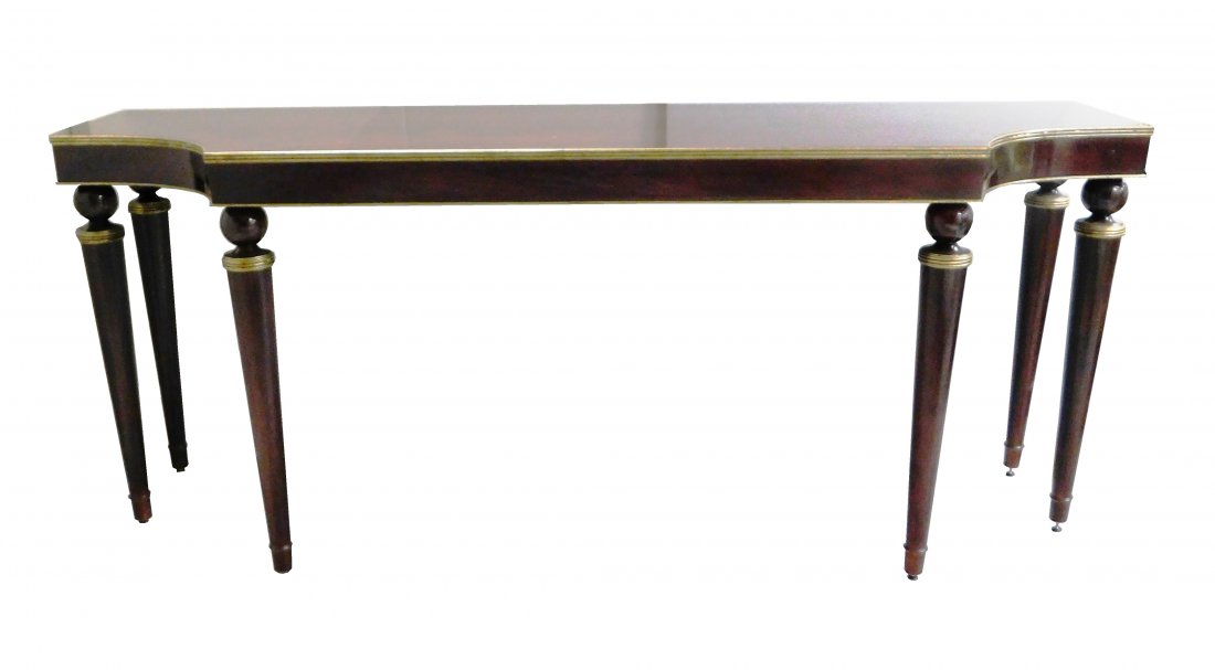 Contemporary Baker console table, oblong top with: Contemporary Baker console table, oblong top with in-cut corners, mahogany finish with gilt trim, six ball over tapered column legs, label verso, wear consistent with age and use including minor abras
