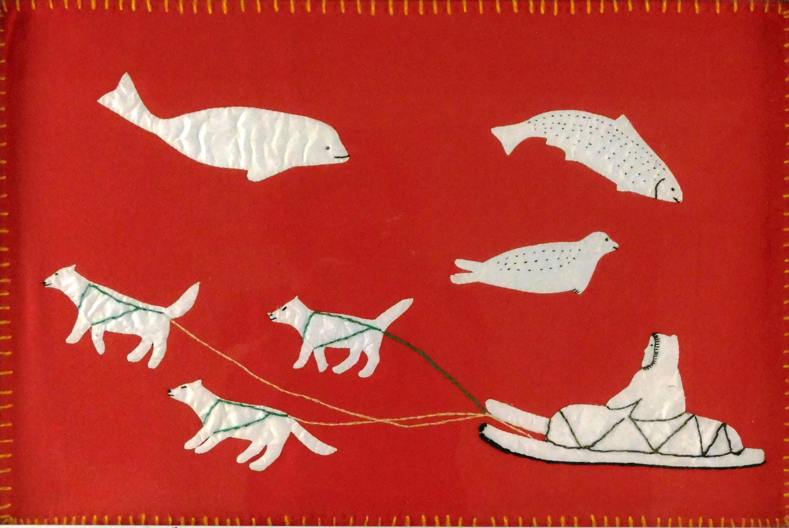 Inuit fabric applique art, red background, white figures including whale, seals and dog sled team,: Inuit fabric applique art, red background, white figures including whale, seals and dog sled team, inscription verso: artist: Daniel Ken (?) Povungnitik, Canada, No 1-04422, Date 12-5-75, Price $33 P.
