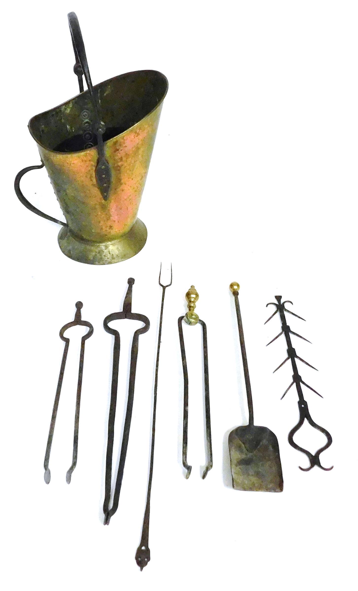 Seven fireplace accessories in copper, brass and iron, details include: copper coal hod with a swing: Seven fireplace accessories in copper, brass and iron, details include: copper coal hod with a swing and stationary handle; game rack; two tine fork; three pair of tongs, one with brass handle; one sh
