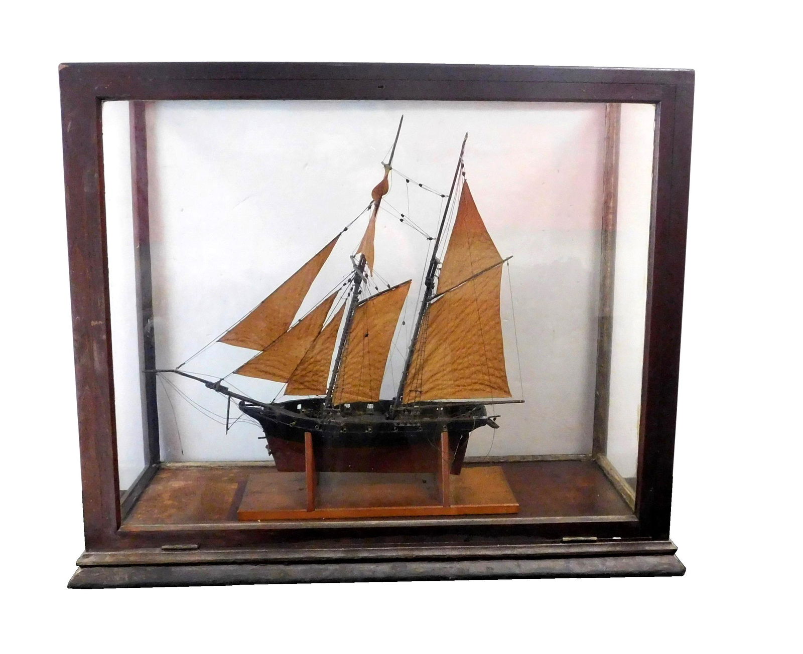 +Two mast ship model in glass case, brig, 20th C., eight brown dyed fabric sails, black and brown: +Two mast ship model in glass case, brig, 20th C., eight brown dyed fabric sails, black and brown painted wooden hull with detailed design to deck including twelve metal cannons, rowboat and metal anc