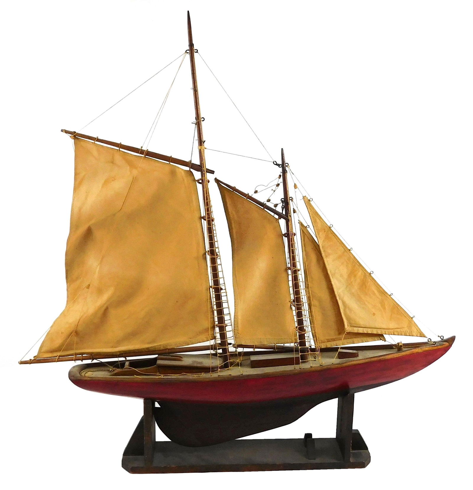 Two mast ship model, 20th C., intricate rigging, fabric sails, red painted wooden hull with detailed: Two mast ship model, 20th C., intricate rigging, fabric sails, red painted wooden hull with detailed design to deck, sails and pulleys are articulated, ship rests on detachable custom stand, staining
