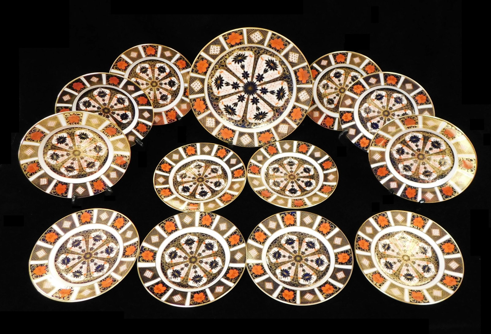 Royal Crown Derby "Old Imari" charger and salad plates, thirteen pieces, all decorated with floral: Royal Crown Derby "Old Imari" charger and salad plates, thirteen pieces, all decorated with floral and geometric motifs rendered in terracotta, navy blue and white glazes with gilt accents, all marked