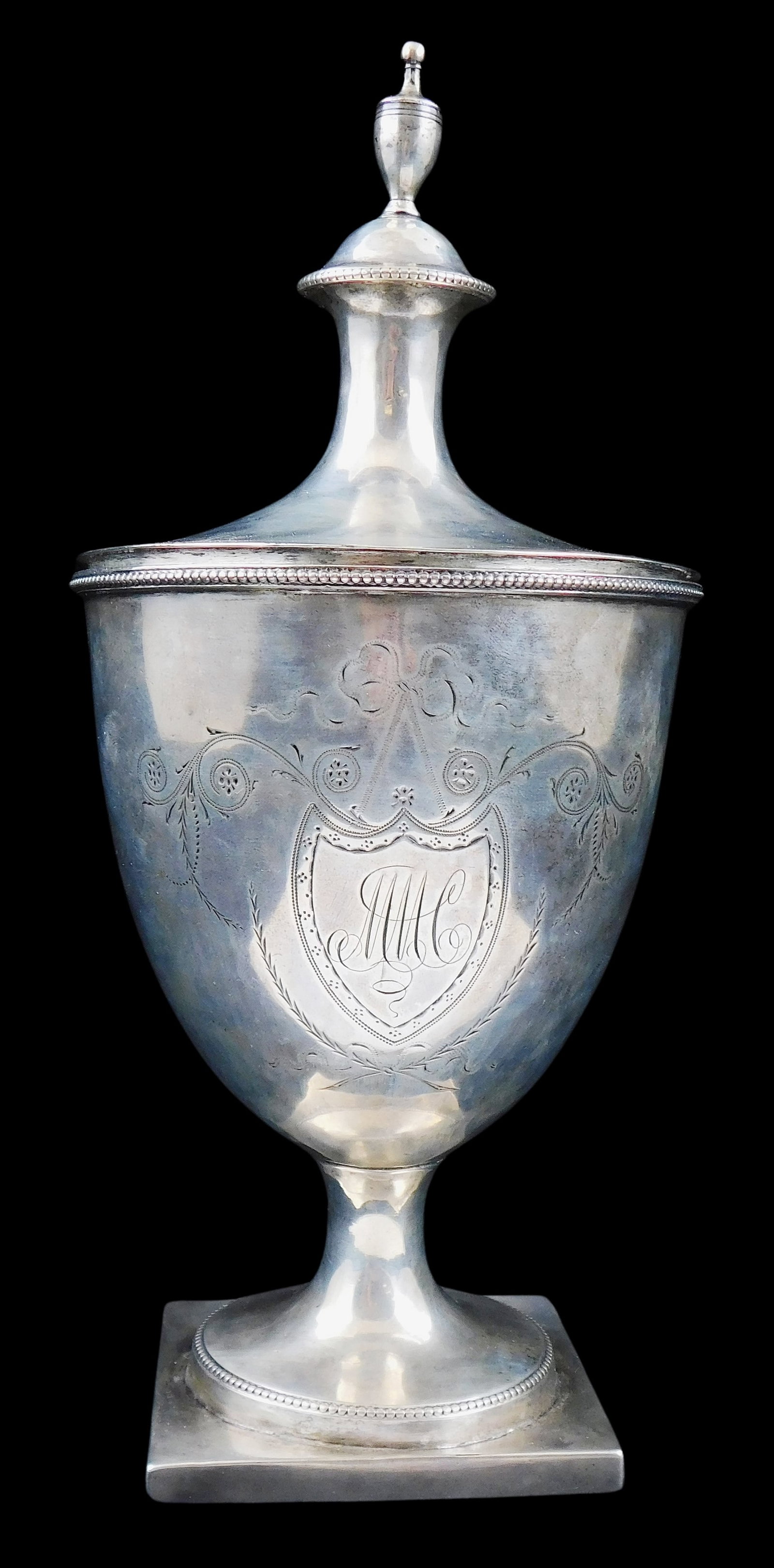SILVER: Early American silver covered urn, no maker's marks viewed, cover with urn finial and disc: SILVER: Early American silver covered urn, no maker's marks viewed, cover with urn finial and disc form rim, rounded body with etched decoration of shield with monogram "MMC", scrolling vines and ribb
